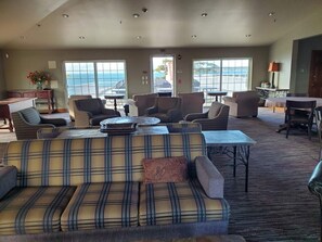 A spacious living area with a large sofa, multiple chairs, a coffee table, and a view of the ocean through large windows.
