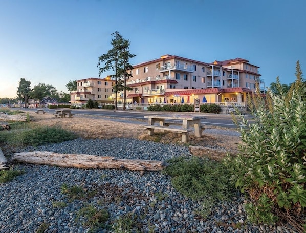 A multi-story hotel with balconies, outdoor seating, and a gravel area with benches.
