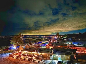 Ein gut beleuchteter Außenbereich mit einem Holzgebäude, Zelten und einer gepflasterten Straße.