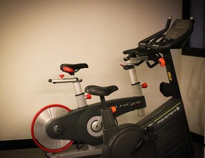 Un vélo d’appartement doté d’un écran numérique, d’une selle rouge et noire et d’une roue rouge.