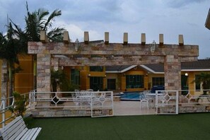 A building with a stone facade, a swimming pool, and outdoor seating. - Stylish Room for Rest & Relaxation | Outdoor Pool Access and Free Parking (Ponta Grossa)