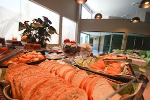 Ein Buffet mit verschiedenen Speisen und einer großen Pflanze im Hintergrund.