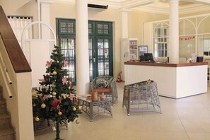 Eine Lobby mit einem Weihnachtsbaum, Korbsesseln, einem Empfangstisch und einer Treppe.