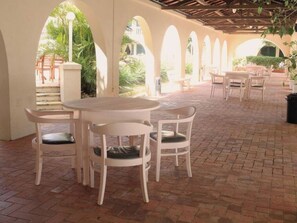 An outdoor patio with a round table and chairs, surrounded by arches, and a brick floor. - Inviting Stay with Comfort and Tranquility | Outdoor Pool & Free Breakfast (Rio Grande)