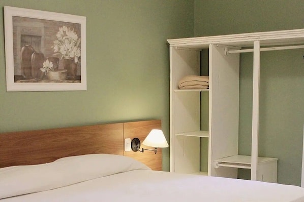 A hotel room with a bed, a nightstand, a lamp, a wardrobe, and a framed picture on the wall. - Inviting Stay with Comfort and Tranquility | Outdoor Pool & Free Breakfast (Rio Grande)