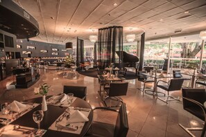 Un restaurante espacioso con varias mesas, sillas y un piano de cola.