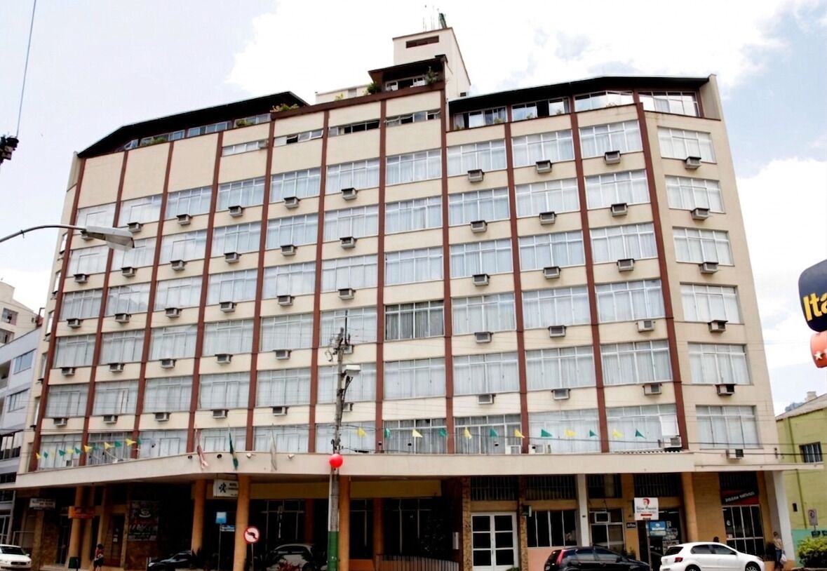 Um hotel de vários andares com fachada bege, várias janelas e aparelhos de ar condicionado.