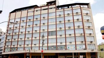 Um hotel de vários andares com fachada bege, várias janelas e aparelhos de ar condicionado.