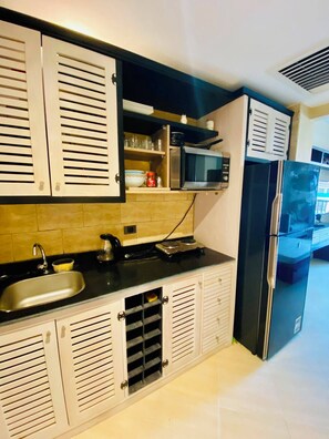 Eine Küche mit einem schwarzen Kühlschrank, einer Mikrowelle und einem Spülbecken.