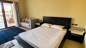 Hotellihuone, jossa on suuri sänky, yöpöytä, sivupöytä, sohva ja näkymä ulos.