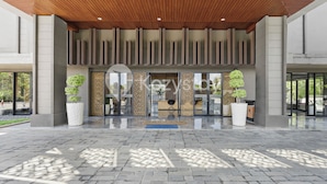 Una entrada de edificio moderna con techo de madera, puertas de cristal y plantas en macetas.