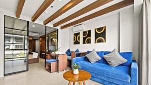 Un salón moderno con un sofá azul, una mesa de centro de madera y una pared divisoria de vidrio.