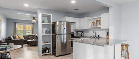 A modern kitchen with white cabinetry, stainless steel appliances, and a granite countertop.