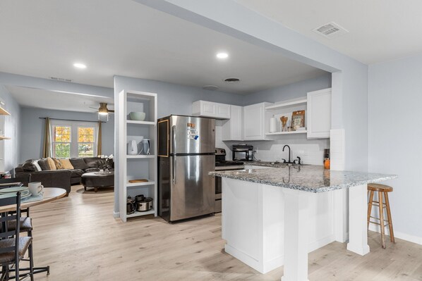 A modern kitchen with white cabinetry, stainless steel appliances, and a granite countertop.