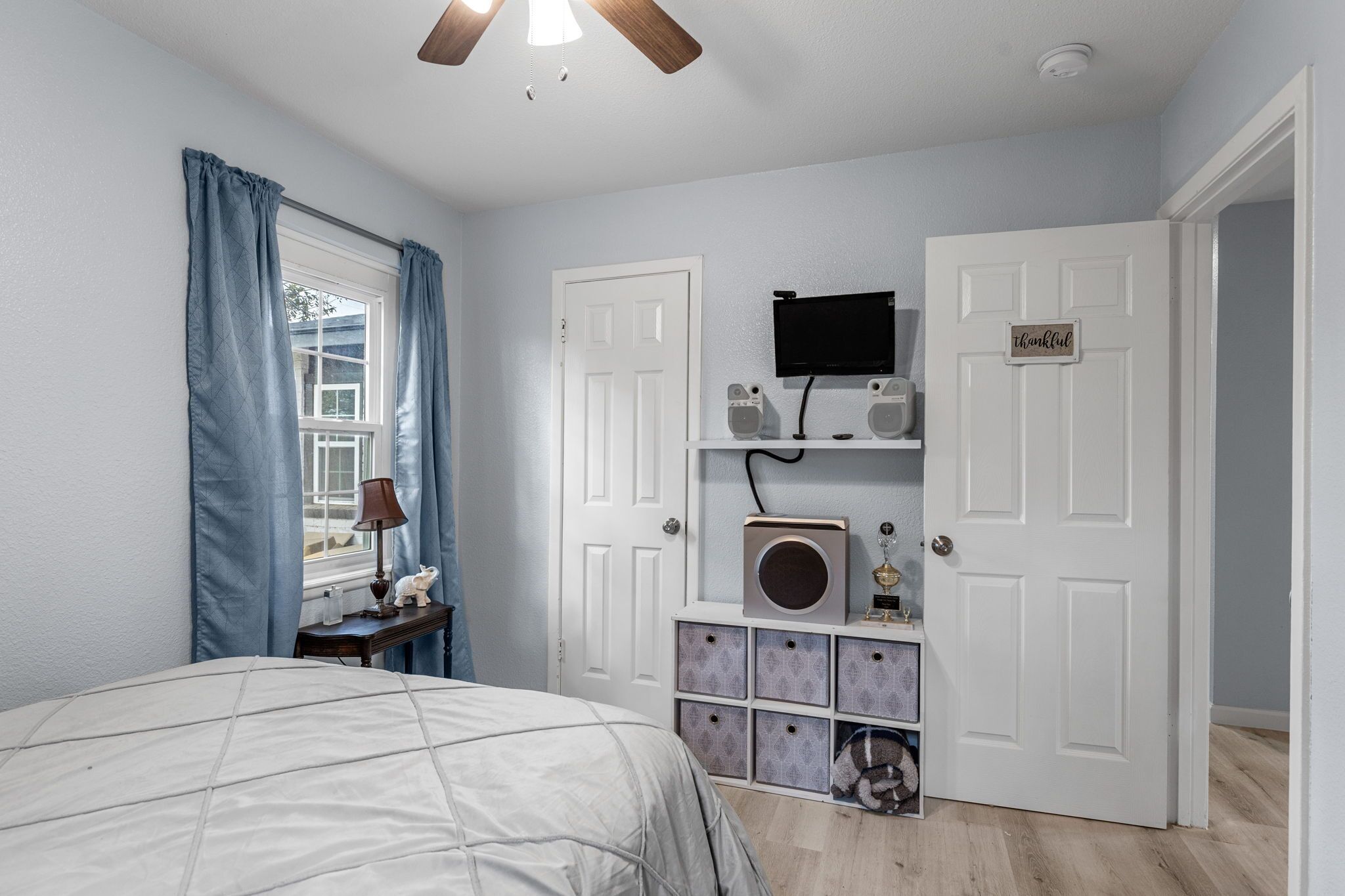 Une chambre à coucher comprenant un lit, un bureau, une lampe, un téléviseur et des boîtes de rangement.