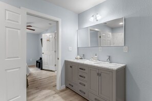 A bathroom with a large mirror, a sink, and cabinets.