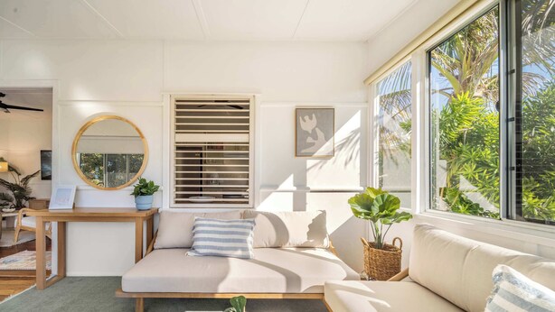 Uma sala de estar moderna com um sofá modular, um espelho redondo e uma área de jantar com mesa e cadeiras.