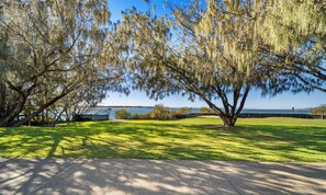 A park with trees, a grassy area, and a body of water in the background. - Aloha Sands - Golden Beach Escape, Dog-Friendly (Caloundra Region)