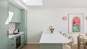 Une cuisine moderne dotée d’un îlot central, de meubles de couleur claire et d’un coin repas avec des chaises en bois.