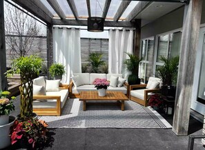 Un patio soleado con un conjunto de sofás, una mesa de centro de madera y plantas en macetas.