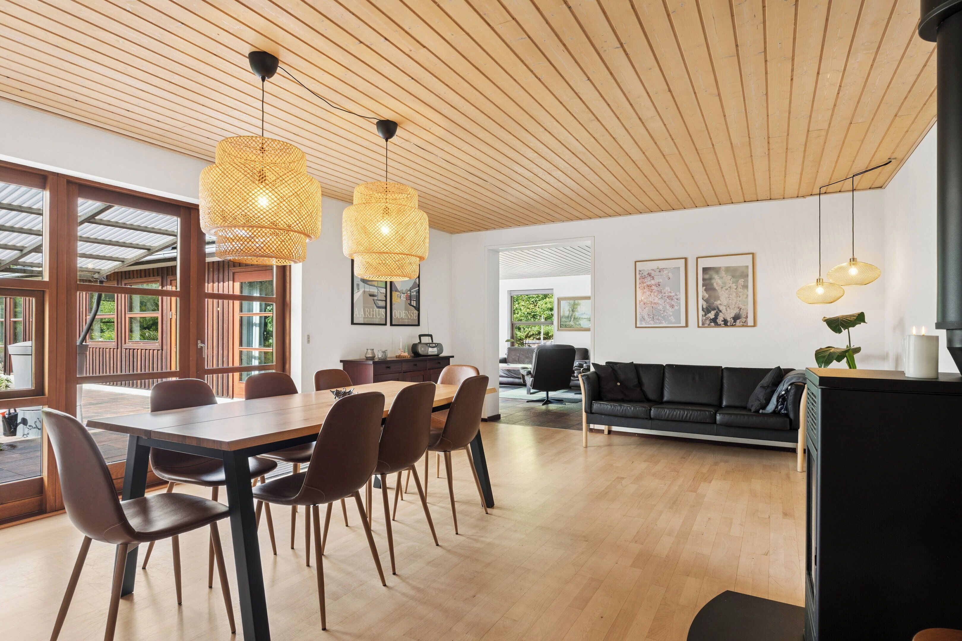 A modern interior with a dining area, a black sofa, and wooden flooring.