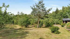 A grassy area with trees and a small building with a sloped roof. - Holiday home with billiards, shelter & fire pit (Silkeborg)