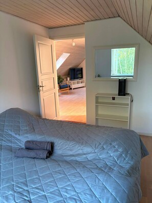 Ein Schlafzimmer mit einem Bett, einem Fenster und Blick auf einen Wohnbereich.