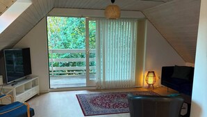 A spacious living room with a television, a sofa, a chair, and a floor lamp. - Scenic home in Virklund (Virklund)