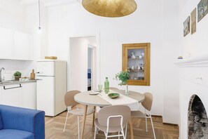 A modern kitchen with white cabinets, a refrigerator, and a dining area with a table and chairs. - Italian Experience-Suite Sinfonia Blu (Bevagna)