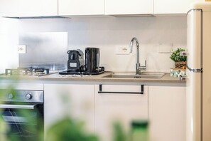 Uma cozinha moderna com fogão a gás, cafeteira e geladeira de aço inoxidável.