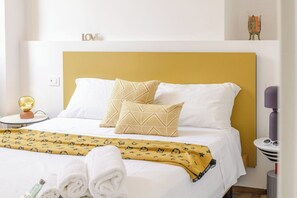 A hotel room with a bed, pillows, a bedside table, a lamp, and a wall-mounted shelf with a decorative item. - Italian Experience - Suite Sinfonia Oro (Bevagna)