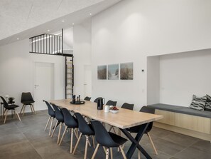 A modern dining area with a long table, black chairs, and a bench.