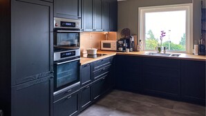 Uma cozinha moderna com armários escuros, forno embutido, micro-ondas e m áquina de café.