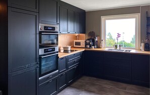A modern kitchen with dark cabinetry, a built-in oven, a microwave, and a coffee maker. - Gorgeous home in Tingvoll with house sea view (Tingvoll)