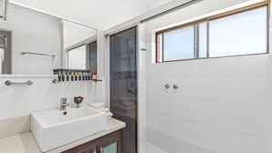 Un bagno moderno con un lavandino bianco, uno specchio e un angolo doccia.