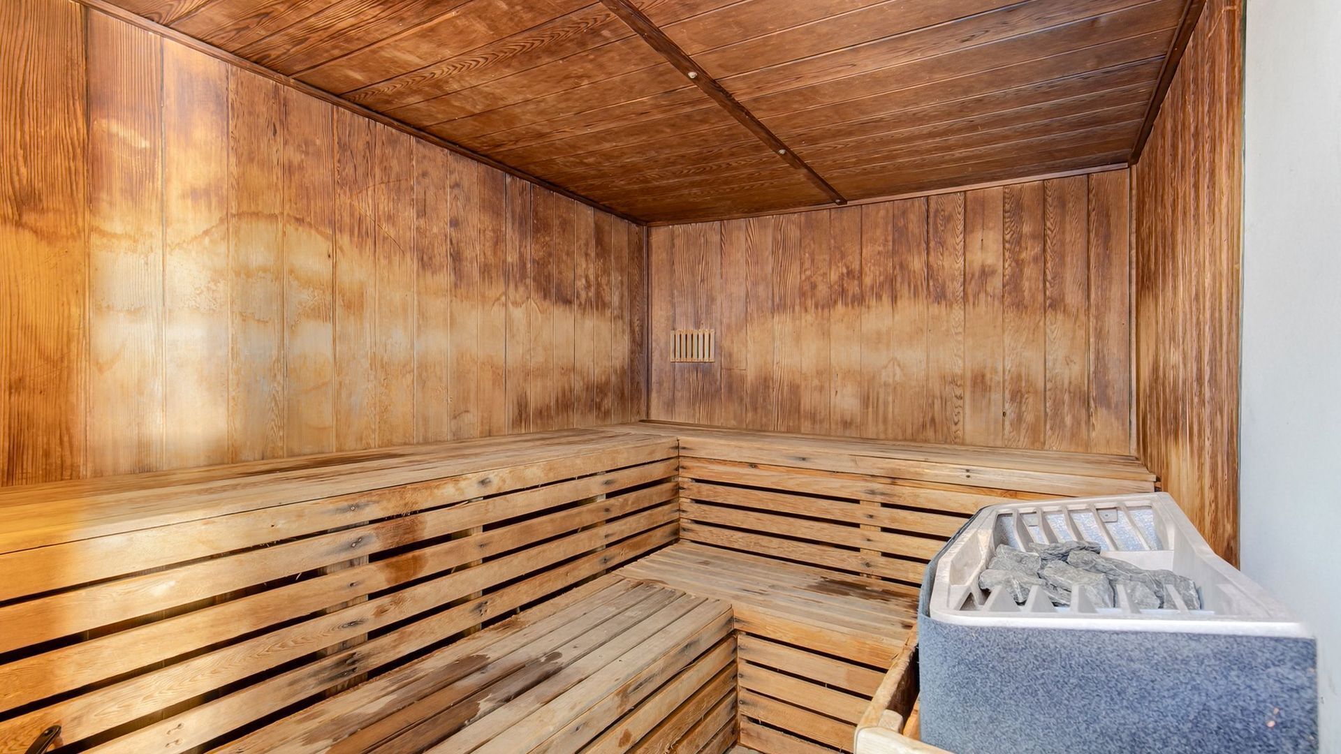 Un sauna avec des bancs en bois et un élément chauffant en pierre.