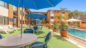 Ein Poolbereich mit Liegestühlen, Sonnenschirmen und einem Tisch.