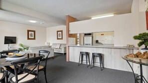 A modern hotel room with a dining area, a kitchen, and a living space. - Sandcastles 219 - across the street from Park Beach in Coffs Harbour (Coffs Harbour)