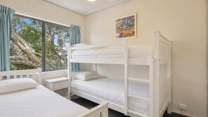 Ein Zimmer mit Etagenbetten, einem fenster mit Vorhängen, einem Nachttisch und einem Bild an der Wand.
