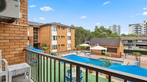 A residential building with a swimming pool, lounge chairs, and a covered patio area. - Sandcastles 219 - across the street from Park Beach in Coffs Harbour (Coffs Harbour)
