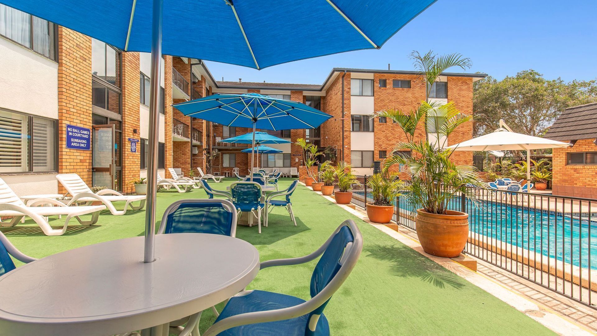 A poolside area with sun loungers, umbrellas, and a pool.