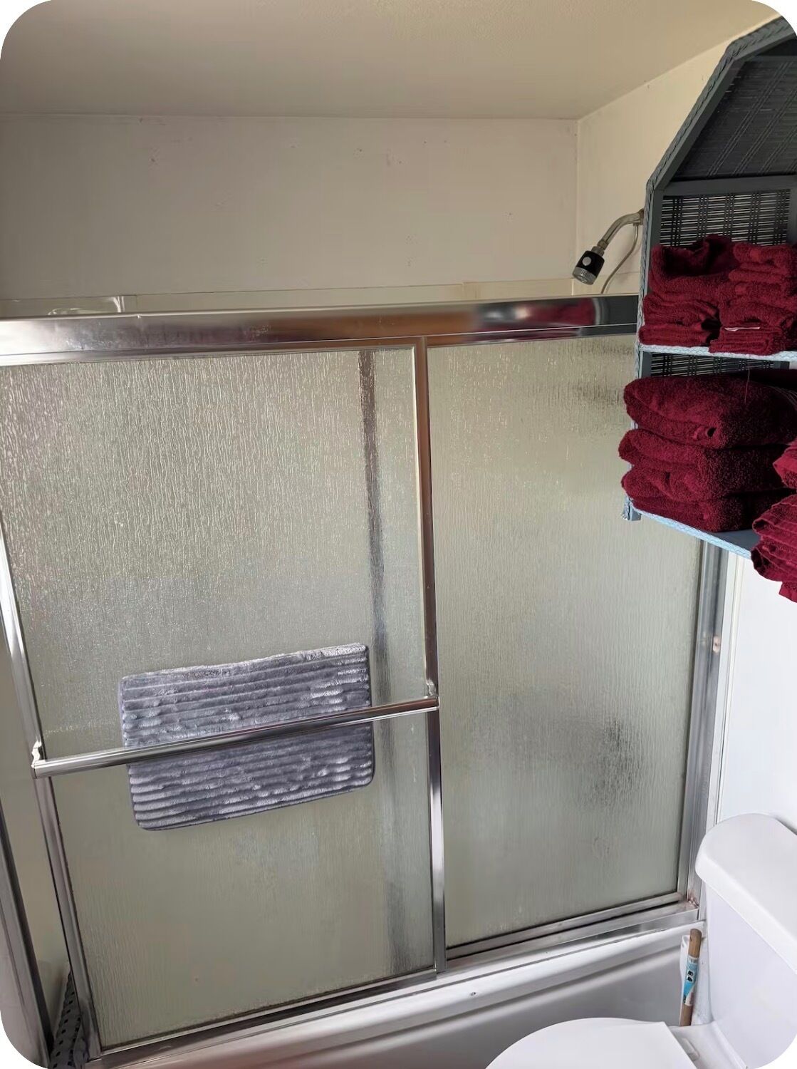 Aseo con mampara de vidrio satinado y perchero.