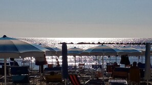 A beach with rows of umbrellas and lounge chairs, providing shade and seating for beachgoers. - A cozy place for a beach vacation for nice people (and their pets) (Lido degli Scacchi)