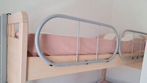 A bunk bed with a headboard, a mattress, and a lower bunk with a striped pillow.