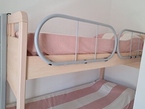 A bunk bed with a headboard, a mattress, and a lower bunk with a striped pillow.