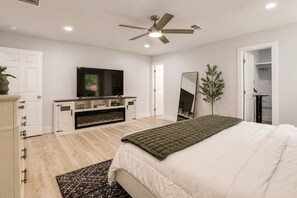 Une chambre à coucher comprenant un lit, un téléviseur, un ventilateur de plafond et une armoire.