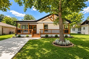 A single-story house with a front porch, a tree in the yard, and a well-maintained lawn.