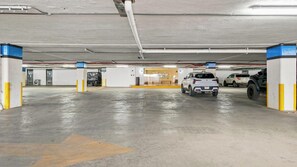 Eine unterirdische Tiefgarage mit mehreren Stellplätzen, einem sichtbaren Ausgang und einem Gebäudeeingang im Hintergrund.