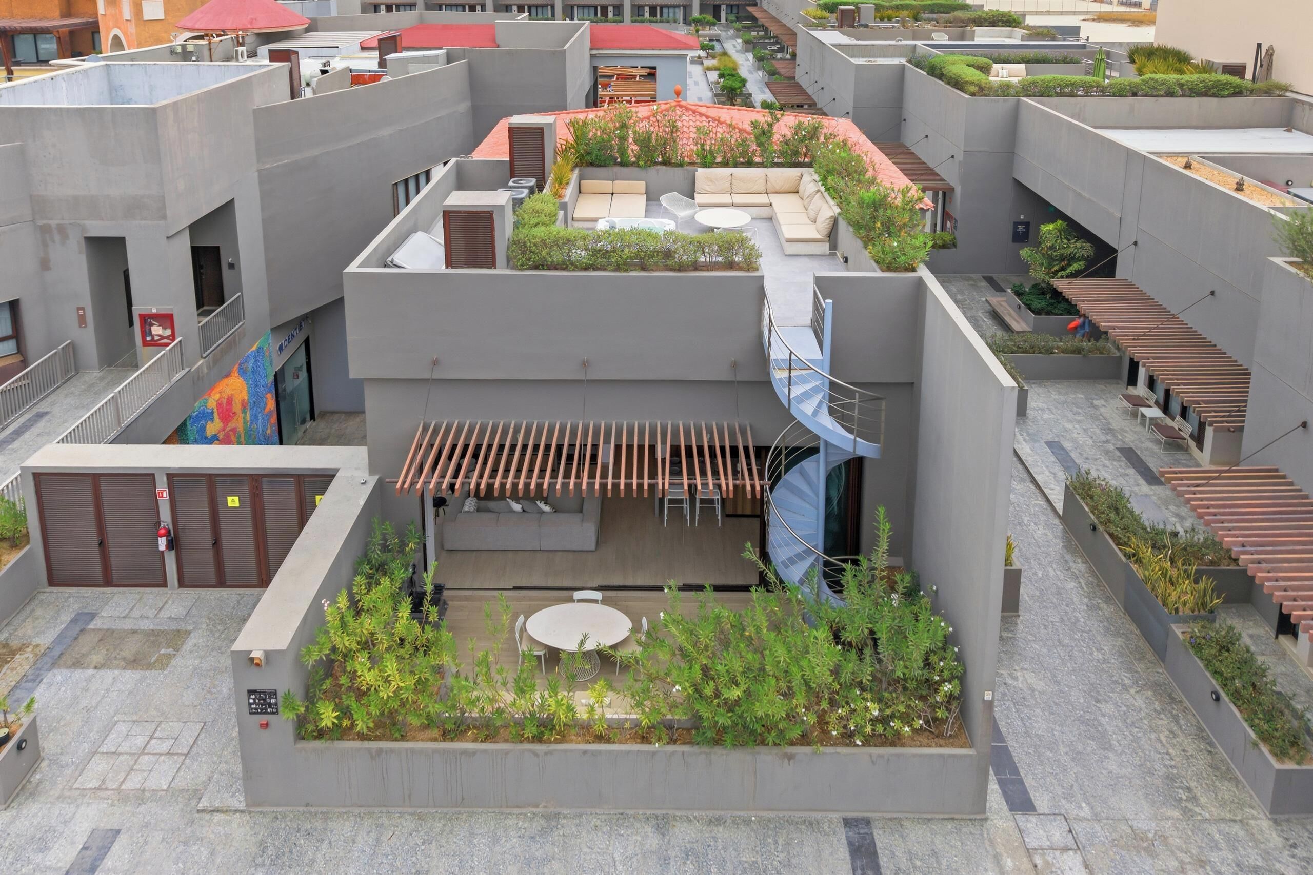Una terraza en la azotea con zonas de estar, una pequeña mesa y una escalera.