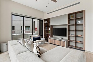 A modern living room with a sofa, a TV, and built-in shelves. - Paraíso Residence: Luxury in the Heart of the Marina (Cabo San Lucas)